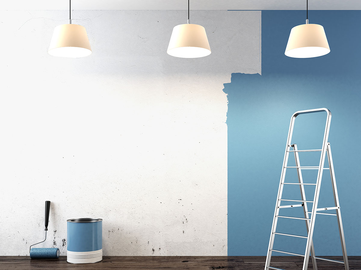 A wall half painted blue in an apartment