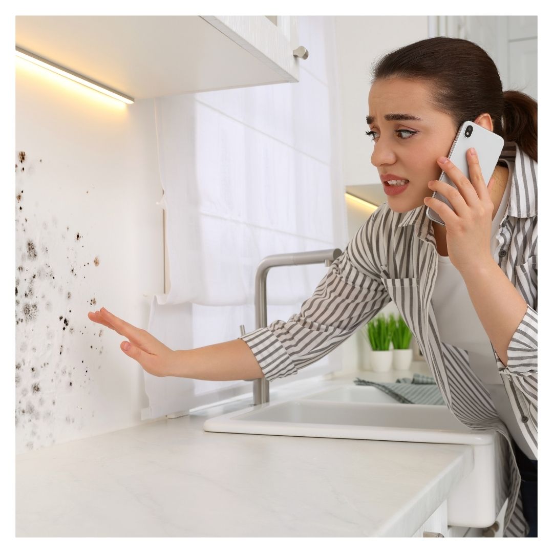 a woman looking at mold while on the phone