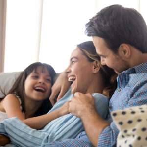 A diverse family relaxes on a modern couch in a clean, well-lit living room.